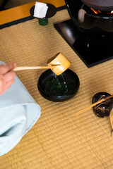 Japanese woman, tea master, Sen Rikyu, hands using a Hishaku bamboo ladle to pour hot water into chawan tea bowl filled with matcha powder during a Japanese traditional tea ceremony © A Certain Aesthetic