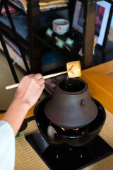 Japanese woman, tea master, Sen Rikyu, hands using a Hishaku bamboo ladle to pour water back into chagama kettle during a Japanese traditional tea ceremony © A Certain Aesthetic