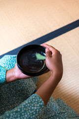 Black woman hands turning chawan tea bowl after drinking matcha tea during Japanese traditional tea ceremony 