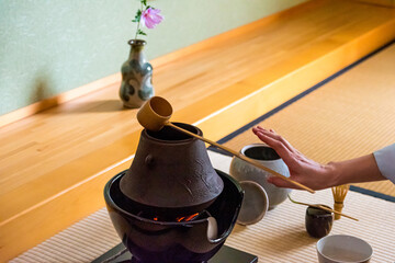 Japanese woman, tea master, Sen Rikyu, hands performs ritual to lay down Hishaku bamboo ladle on...