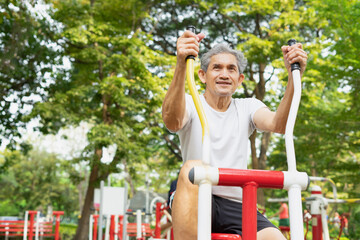 Fototapeta na wymiar A healthy senior man with grey hair doing exercise on outdoor fitness equipment in the city park, concept for elderly people lifestyle, health, health care ,wellness