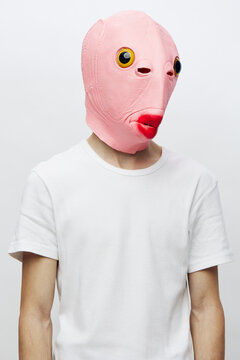vertical portrait of a man in a pink mask on a light background