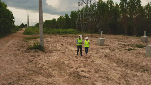 Male and female environmental engineers inspect the forest for the development of the high voltage pole foundation construction site. Biologists out in the field examine eucalyptus forests with data r