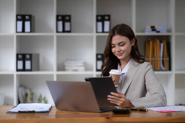Photo of cheerful young woman working using computer laptop concentrated and smiling at office