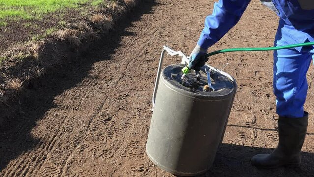 Worker man with hose filling soil ground hardener roller with water. Static shot