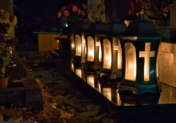 a candles with crucifix in the cemetery on the grave at night, all Saints Day