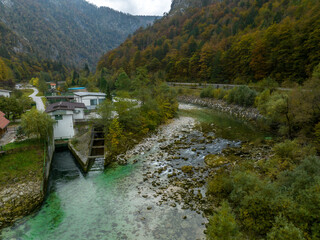 Fototapeta premium Slovenia - View of the Slovenian river with mountains and autumn colors on the trees from drone view