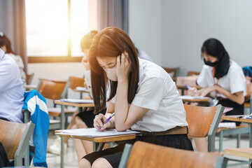 College students writing on final examination papers in the classroom concentrately