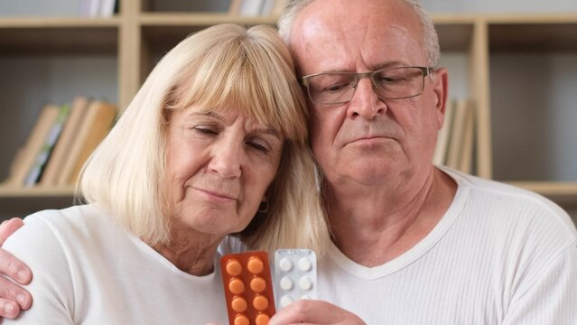 Upset Senior Elderly Couple Holding Pills And Looking At Camera. Sick Elderly People, Depressed