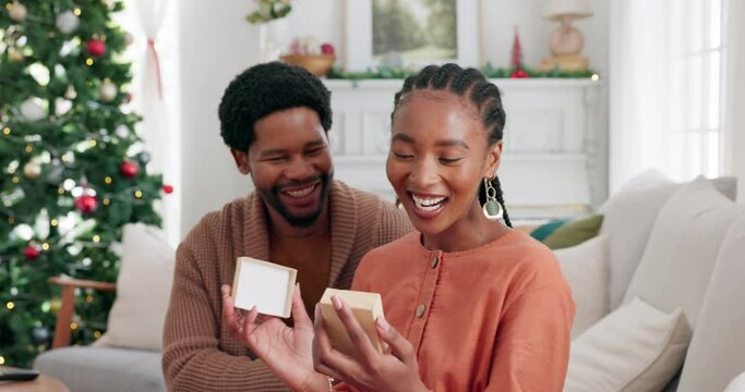 Wow, christmas and black couple with a surprise gift in celebration of a happy holiday in a lovey home together. Smile, happiness and African man giving an excited black woman a gift box present