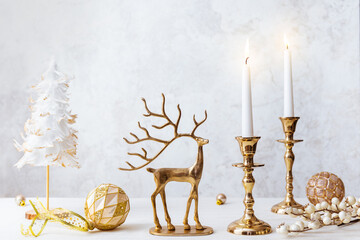 Cozy still life with burning candles, figure of deer and Christmas decorations on pastel light background. Christmas composition for home interior..