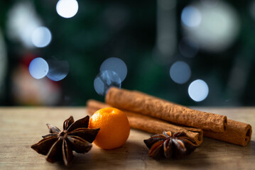 Cinnamon, star anise, tangerine, and kumquat lie on a wooden table on the background of a Christmas...