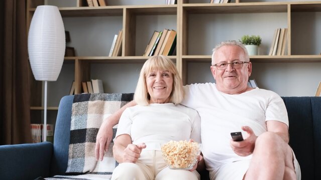 Elderly Couple Of Sports Fans Watching Sports TV Games Sitting Together On The Couch