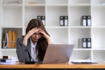 Asian businesswoman are serious at work causing headache stressed out with documents with a laptop at the office.