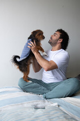 man in his bedroom playing with his dog, man holding his dog in his lap