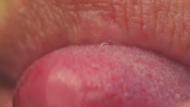 Women's lips close up. The girl sticks out the tip of her tongue from closed pink lips. Sexy seductive video.