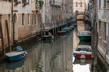 Fototapeta na wymiar Small, Venetian canal, located off the main areas of Venice. Small boats can be seen moored against the doors opening up to the water