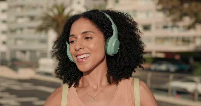 Black woman, headphones and listening to music on urban city travel while streaming, dancing and outdoor for travel and fun. Female, smile and audio technology on street of Miami for travel holiday