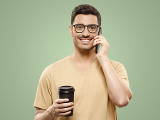 Guy in beige t-shirt and glasses, standing with takeaway coffee cup talking on phone with colleague