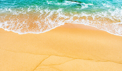Golden sand beach seashore with white foamy wave from blue sea on daylight