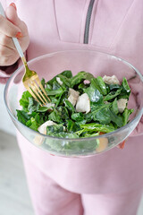 woman hands holding bowl of healthy salad with spinach and peach