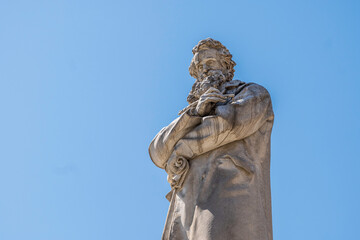 Detail of an ancient statue of an old man, framed against a deep blue sky.