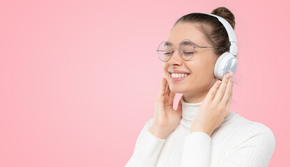 Banner of smiling female in glasses, enjoying music in wireless headphone with eyes closed