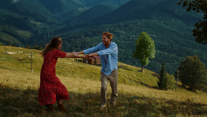 Cheerful couple dance mountains. Happy lovers have fun hold hands at nature view