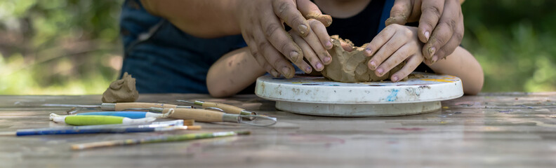 Close up pottery teacher hands teaching kid to creat model clay in pottery workshop, art and craft 
Kid Artist concept