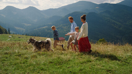 Parents kids walking dog on mountain hill. Girl with mother holding husky leash. © stockbusters