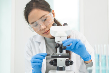 Medical development research laboratory, science young woman scientist in glasses, glove looking under microscope for test analysis samples in lab. Microbiology, analysing biochemicals for medicine