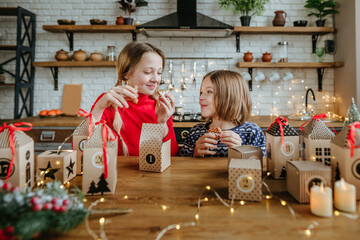 Sisters opening gift boxes of advent calendar with Christmas cookies