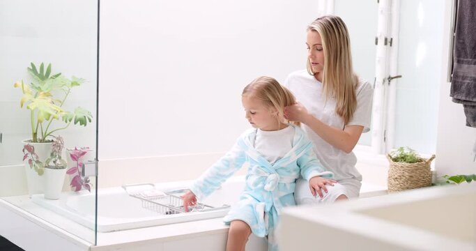 Morning, mother and daughter in bathroom with hair brush for grooming care routine in family home. Motherhood, child and mama brushing hair of young kid in house and getting ready for the day.