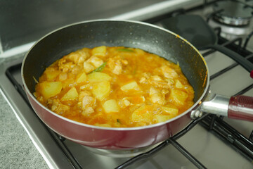 cooking chicken curry in a cooking pan 