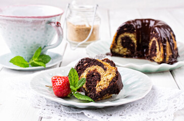Traditional marble cake gugelhupf with chocolate icing and a strawberry served as close-up on a design plate