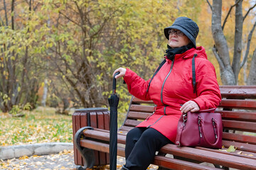 An elderly woman is sitting on a bench.