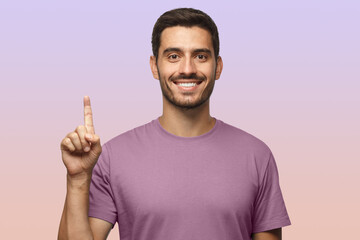 Attractive young man in purple t-shirt pointing up with his finger isolated on purple