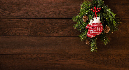 Merry Christmas and Happy New Year! Mittens, fir branches and cones on a wooden background
