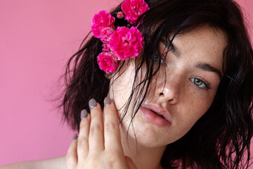 Naklejka premium a beauty brunette woman portrait,a pink flower in the hand near face
