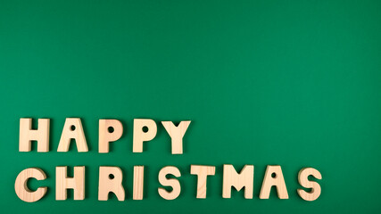 Happy christmas sentence made by wood letters on green background.