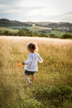 a beautiful little girl in a white shirt walks in the evening in the field