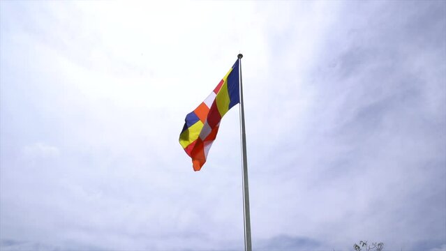 Beautiful colorful Buddhist flag flutters in the wind against the sky