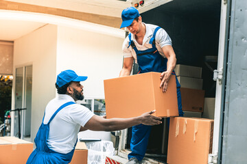 House moving staff is lifting box full of stuff ready for leading into their van infront of customer house.