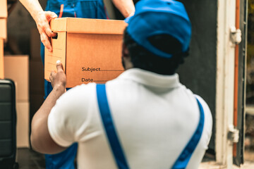 House moving staff is lifting box full of stuff ready for leading into their van infront of customer house.