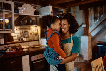 Cheerful African American mother and daughter have fun while preparing lunch for Thanksgiving day in kitchen.