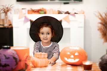 Fototapeta premium Girl kid child carving traditional Halloween jack-o-lanterns with scary face for party at home