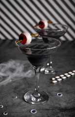 Halloween black cocktail in glasses with candy eyeball. Party festive celebrate concept.