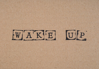 Cardboard with words Wake Up made by black alphabet stamps.