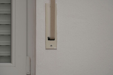 close-up mechanism of blinds on a white wall near the window, part of a white plastic window with...
