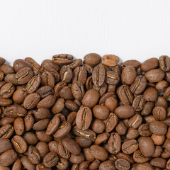 Coffee beans laid out in one wide row on a white background, place for inscription and advertising.